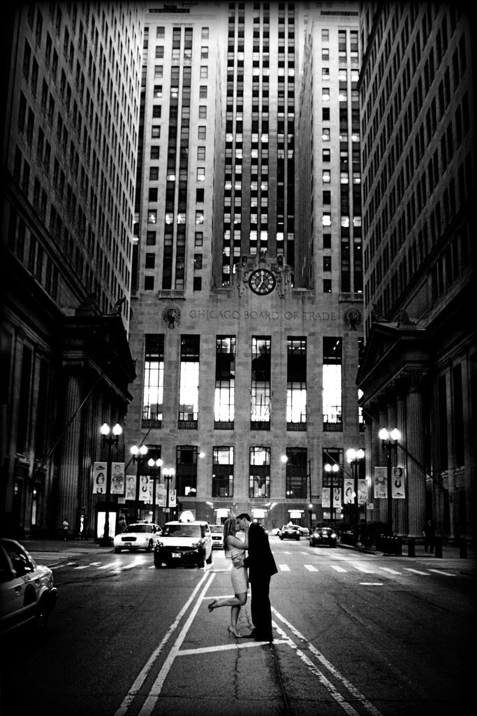 couple kissing in middle of downtown road with Chicago Board of Trade building in background